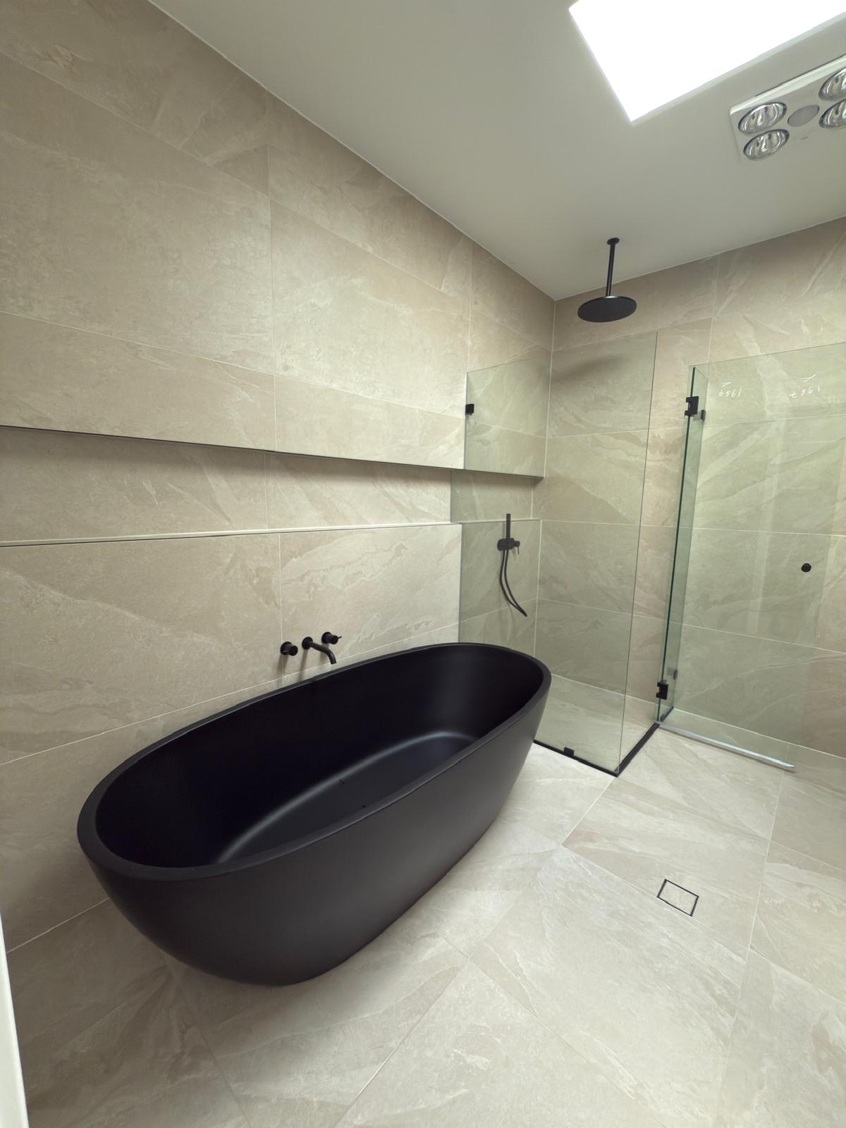 Black freestanding bath under skylight — Gerringong | Shellharbour Plumbing